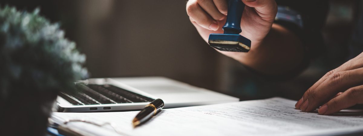 Man stamping approval of work finance banking or investment marketing documents on desk. Man stamping approval of work finance banking or investment marketing documents on desk.