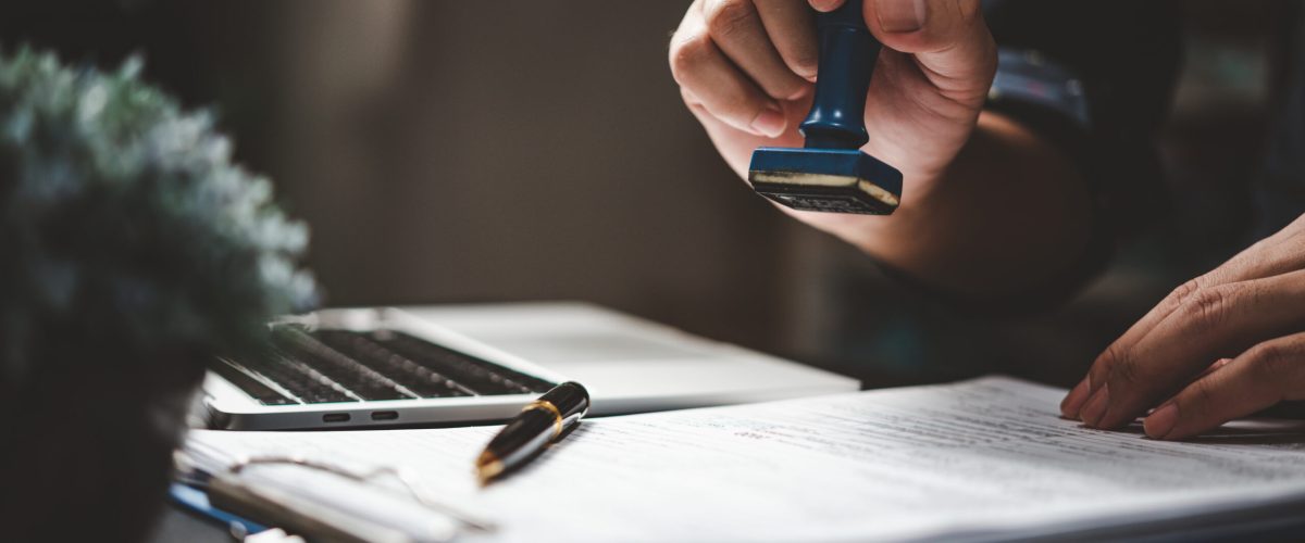 Man stamping approval of work finance banking or investment marketing documents on desk. Man stamping approval of work finance banking or investment marketing documents on desk.